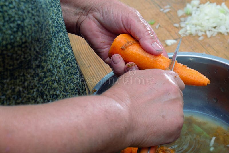 Frauenhand, die rohe frische Karotte schneidet lizenzfreie stockfotos Frauenhand, die rohe frische Karotte schneidet lizenzfreie stockfotos