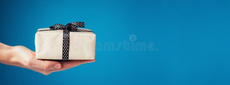 Frauenhand hält Geschenkbox auf Palme auf blauem Hintergrund, Fahne mit Kopienraum lizenzfreie stockfotografie Frauenhand hält Geschenkbox auf Palme auf blauem Hintergrund, Fahne mit Kopienraum lizenzfreie stockfotografie