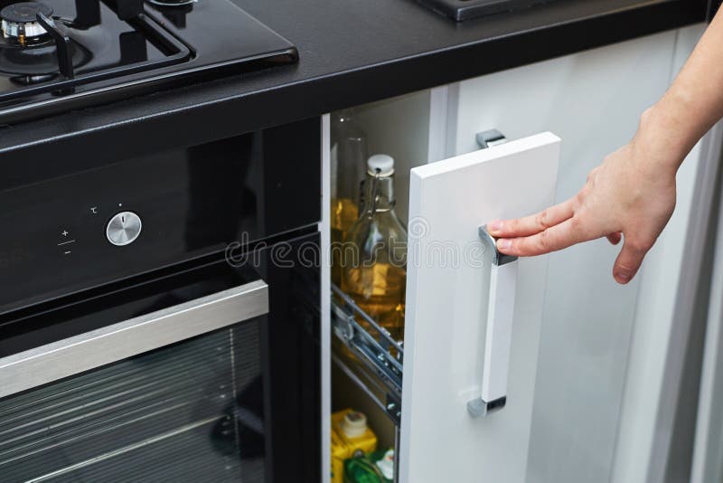 Frauenhand offen ein Küchenspeicherkabinett im modernen Innenraum lizenzfreie stockfotografie Frauenhand offen ein Küchenspeicherkabinett im modernen Innenraum lizenzfreie stockfotografie