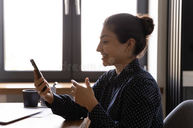 Frauenholdingtelefon der Datenzugriffsseiten-Ansicht lächelnder indisches, das Videokonferenz macht stockfoto