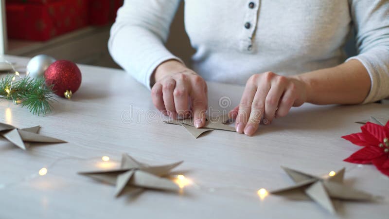 Frauenhände, die Origamipapierstern für Weihnachtsdekoration falten