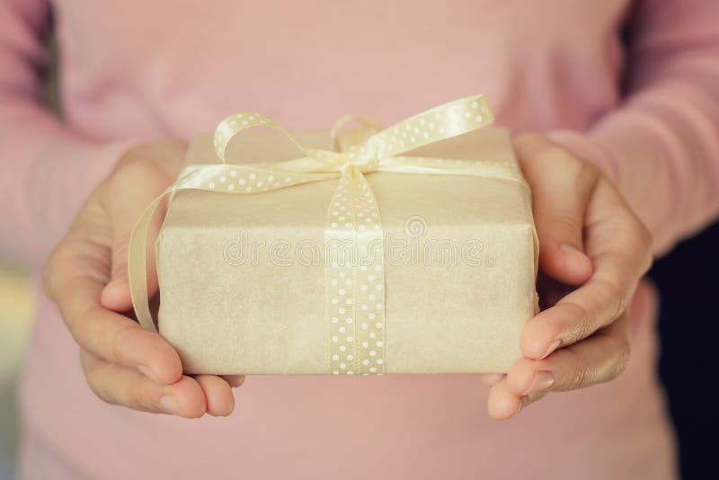 Frauenhände halten eine Geschenkbox eingewickelt im Papier mit Band lizenzfreies stockbild Frauenhände halten eine Geschenkbox eingewickelt im Papier mit Band lizenzfreies stockbild