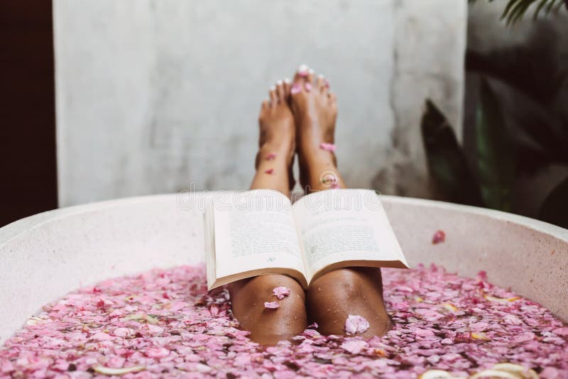 Frauenlesebuch bei der Entspannung in der Badewanne mit den Blumenblumenblättern