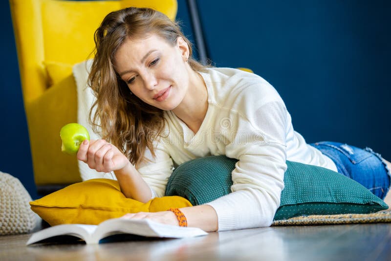 Frauenlesebuch zu Hause und legend auf den Boden nahe bei gelbem Lehnsessel stockfoto Frauenlesebuch zu Hause und legend auf den Boden nahe bei gelbem Lehnsessel stockfoto