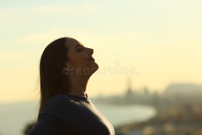 Side view portrait of a woman silhouette breathing deeply fresh air at sunset. Side view portrait of a woman silhouette breathing deeply fresh air at sunset