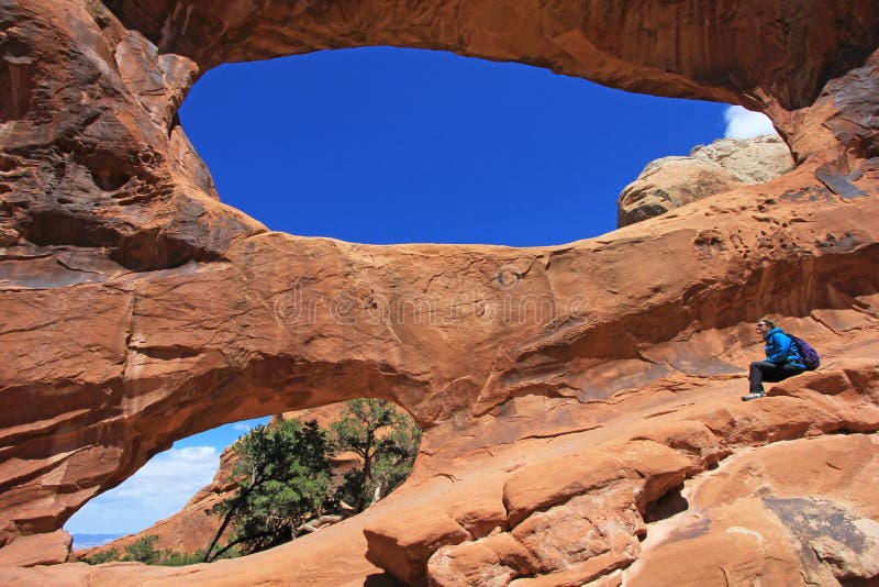 Frauenwanderer wirft an doppeltem O-Bogen an den Bögen Nationalpark, Utah auf stockfotografie Frauenwanderer wirft an doppeltem O-Bogen an den Bögen Nationalpark, Utah auf stockfotografie