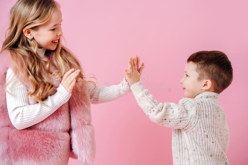 Frații care joacă jocuri de mână. fratele mai mic și sora mai mare. roz închis. stock photo