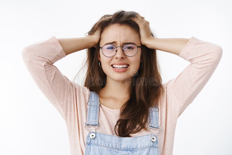 Freaked out woman panic holding hands on head, frowning and clenching teeth being troubled with terrible situation, bothered, cannot think up what do standing in despair, devastated over gray wall. Copy space