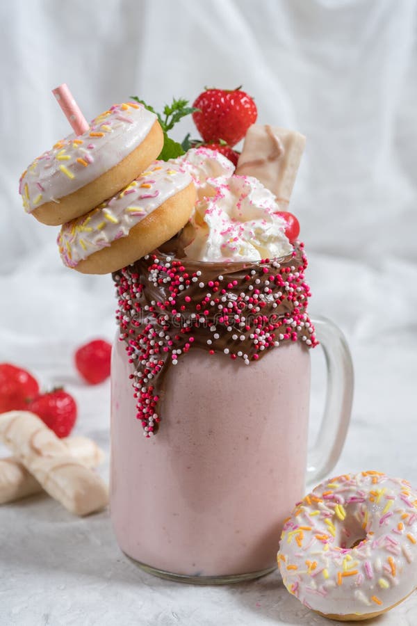 Pink strawberry freakshake milkshake with sweets donut and marshmallow. Pink strawberry freakshake milkshake with sweets donut and marshmallow