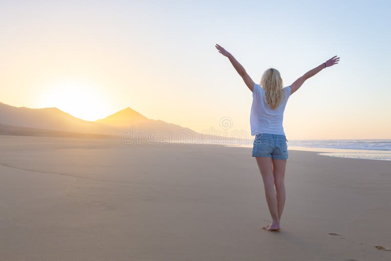Free woman enjoying freedom on beach at sunrise.