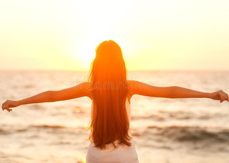 Zdarma žena se těší svobodě pocit, rádi se na pláži při západu slunce.