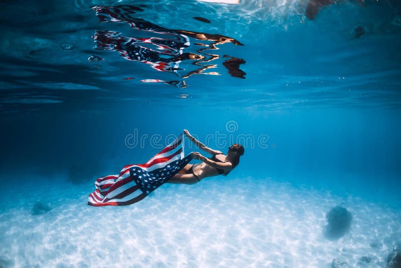 Freediver женщины скользит над песочным дном моря с флагом Соединенных Штатов стоковое фото Freediver женщины скользит над песочным дном моря с флагом Соединенных Штатов стоковое фото