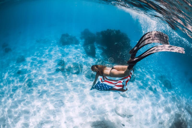 Freediver женщины скользит над песочным дном моря с флагом Соединенных Штатов стоковые изображения rf Freediver женщины скользит над песочным дном моря с флагом Соединенных Штатов стоковые изображения rf