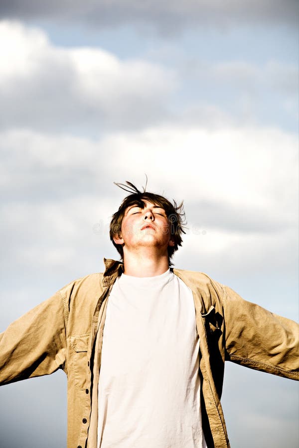 Teen portrait, standing in the wind and reaching arms out against cloudy sky background. Teen portrait, standing in the wind and reaching arms out against cloudy sky background