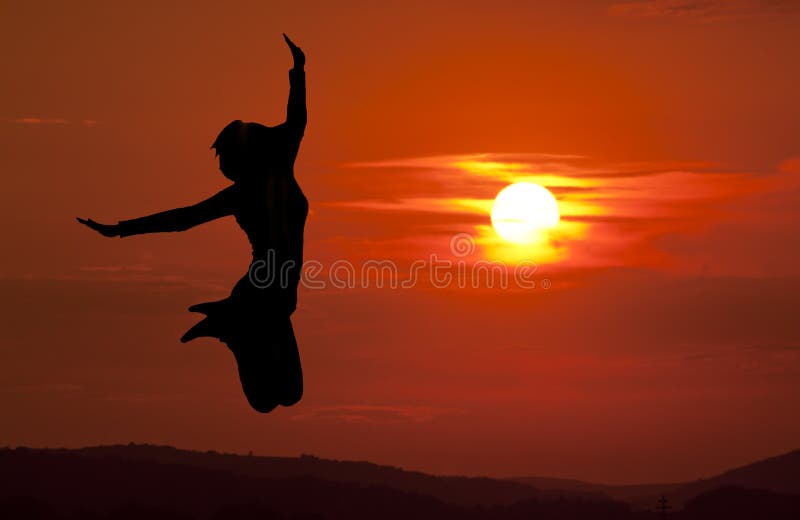 Giovane donna a saltare contro un meraviglioso tramonto.