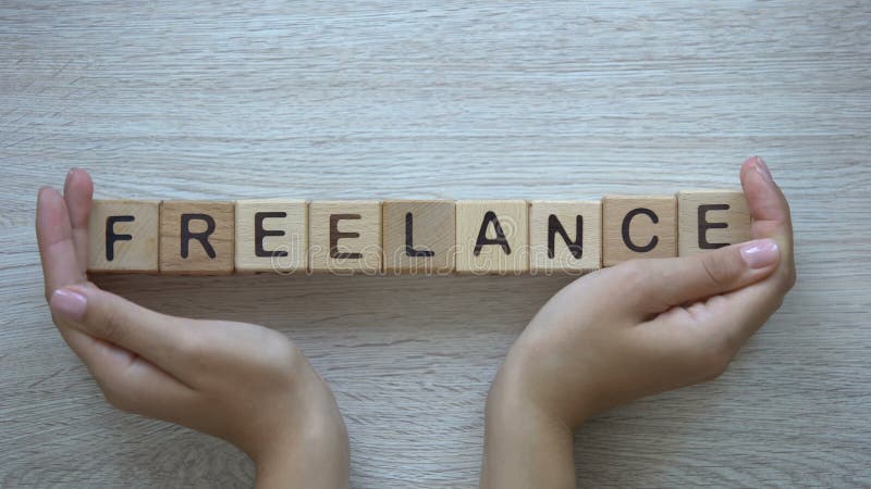 Freelance, hands pushing word on wooden cubes, self employment working from home