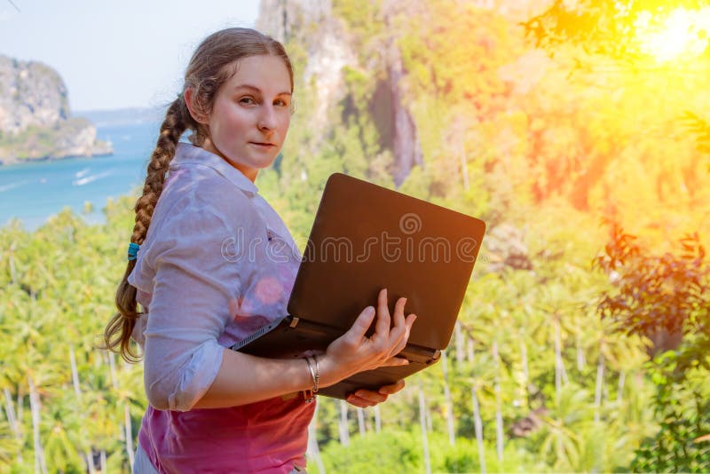 Freelancer da jovem mulher que trabalha com port?til em uma parte superior da montanha com vista no mar e na praia tropical Traba imagens de stock Freelancer da jovem mulher que trabalha com port?til em uma parte superior da montanha com vista no mar e na praia tropical Traba imagens de stock