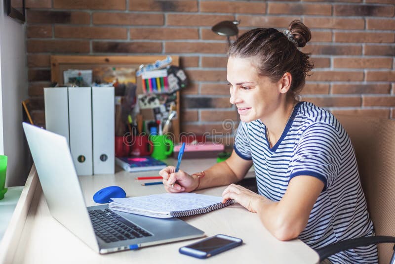 Freelancer de la estudiante que trabaja con el ordenador portátil en casa por el windo fotografía de archivo libre de regalías