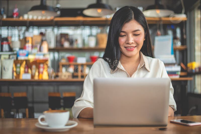 Freelancer de sexo femenino asiático que sonríe cuando usando el ordenador portátil en café Concepto del negocio y del éxito Tema imagen de archivo libre de regalías Freelancer de sexo femenino asiático que sonríe cuando usando el ordenador portátil en café Concepto del negocio y del éxito Tema imagen de archivo libre de regalías