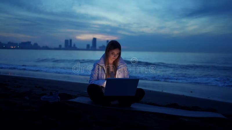 Freelancer femme utilise un ordinateur portable sur la plage de la mer dans la soirée slow mo banque de vidéos