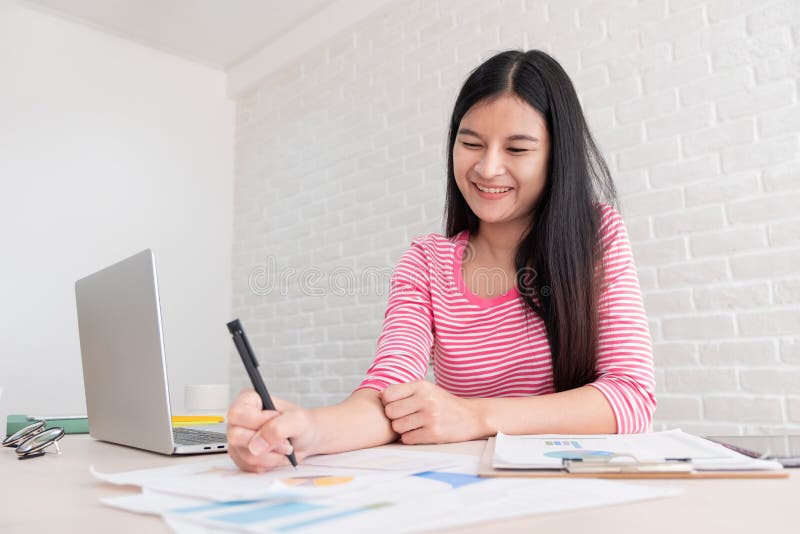 Freelancer fêmea asiático que trabalha no laptop na tabela em b fotos de stock Freelancer fêmea asiático que trabalha no laptop na tabela em b fotos de stock