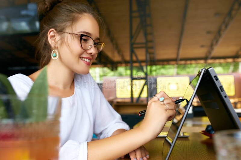 Freelancer mengde de hand van de rasvrouw richtend met naald op het convertibele laptop scherm op tentwijze Aziatisch Kaukasisch stock foto's Freelancer mengde de hand van de rasvrouw richtend met naald op het convertibele laptop scherm op tentwijze Aziatisch Kaukasisch stock foto's