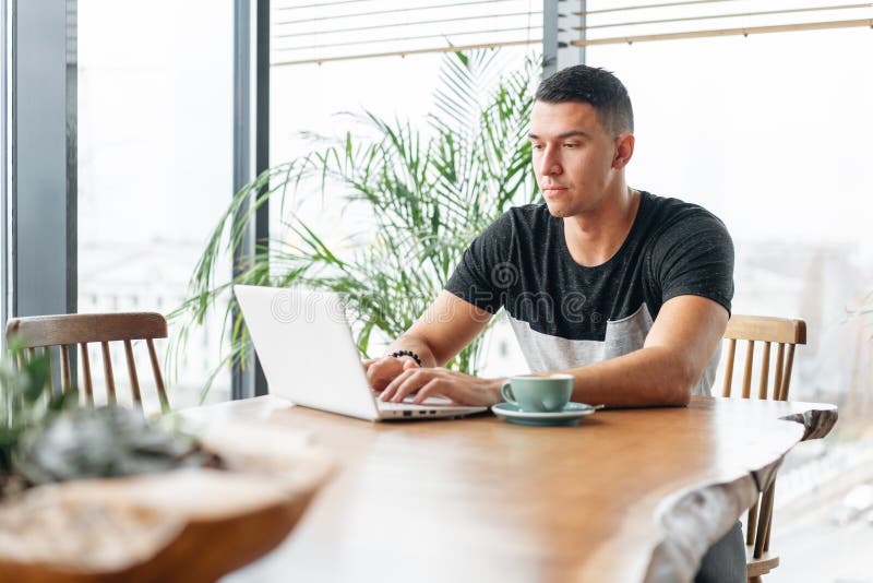 Freelancer Work on Netbook in Modern Coworking. Young Man Drinking