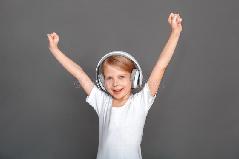 freestyle Niña en los auriculares aislados en las manos grises de la canción que escuchan encima de la sonrisa alegre foto de archivo freestyle Niña en los auriculares aislados en las manos grises de la canción que escuchan encima de la sonrisa alegre foto de archivo