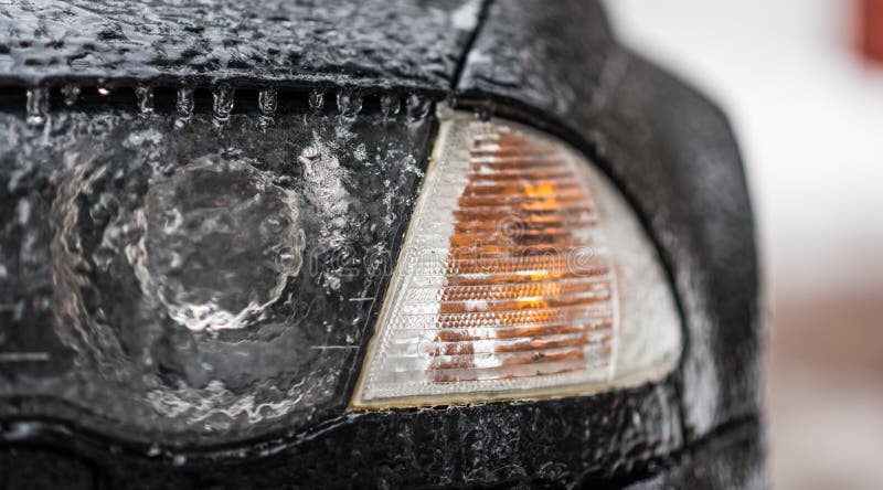 Freezing rain ice coated car. Headlight and signal light on black car covered in freezing rain. Bad driving weather.