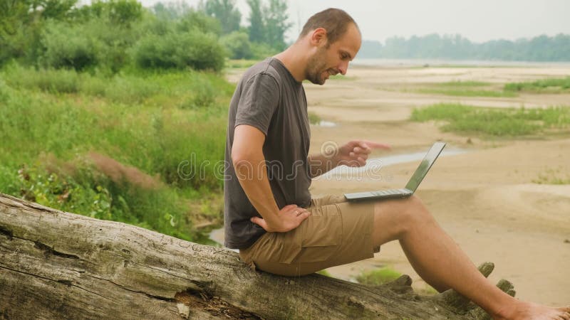 Freiberufler bei einer Online-Konferenz vor dem Hintergrund eines Waldes und eines Flusses.