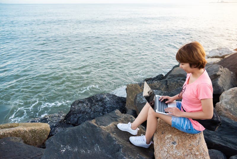 Freiberuflich tätiges Arbeiten der jungen Asiatin mit Laptop stockfotografie