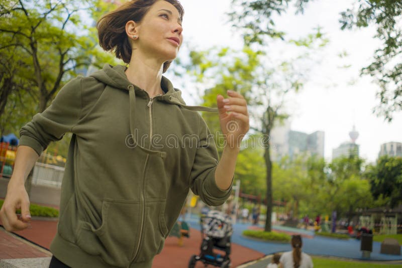 Freienporträt der jungen attraktiven und aktiven Rüttlerfrau im Hoodiespitzenbetrieb und -c$rütteln in der Morgengymnastik an sch lizenzfreies stockfoto Freienporträt der jungen attraktiven und aktiven Rüttlerfrau im Hoodiespitzenbetrieb und -c$rütteln in der Morgengymnastik an sch lizenzfreies stockfoto