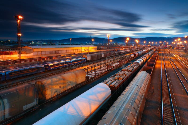 Stazione di merci con treni al tramonto con lunga esposizione.