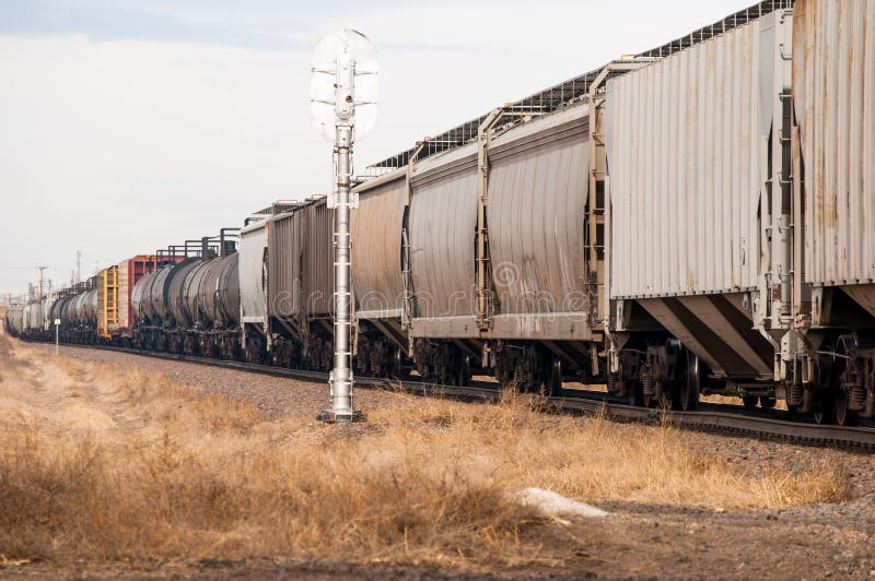 A freight train passing a railrod signal.