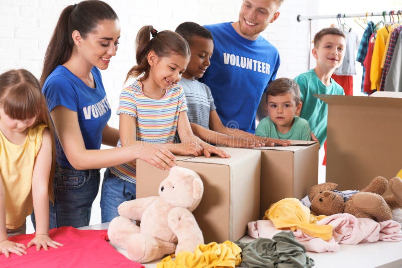 Freiwillige mit den Kindern, die Spendenwaren sortieren stockbild Freiwillige mit den Kindern, die Spendenwaren sortieren stockbild