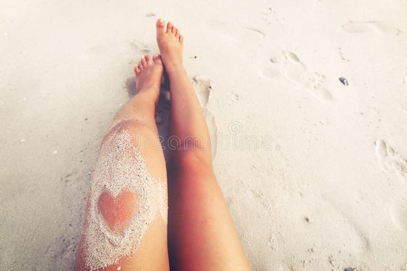 Freizeit im Sommer - Schönheitssonnenbräune entspannen Sie sich auf Strand mit Sand der Herzform
