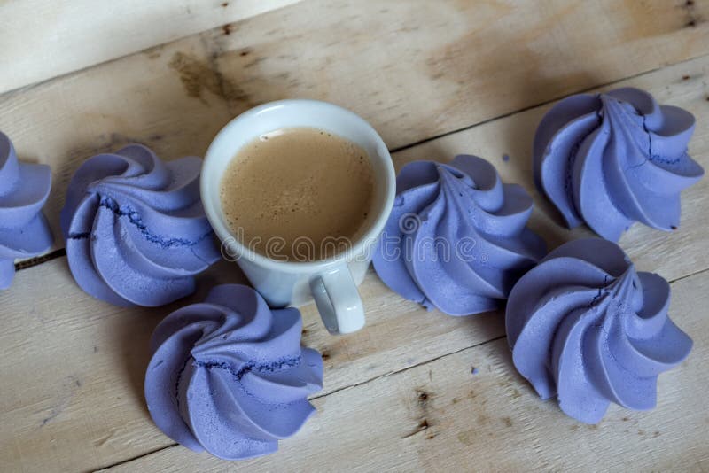 French blue meringue cookies and cup of coffee on wooden background. Food, delicate.