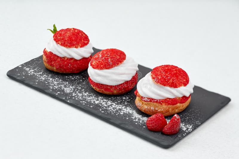 French Cakes with strawberry cream shanti. aery brewing cake on black shale. Restaurant composition on white background.