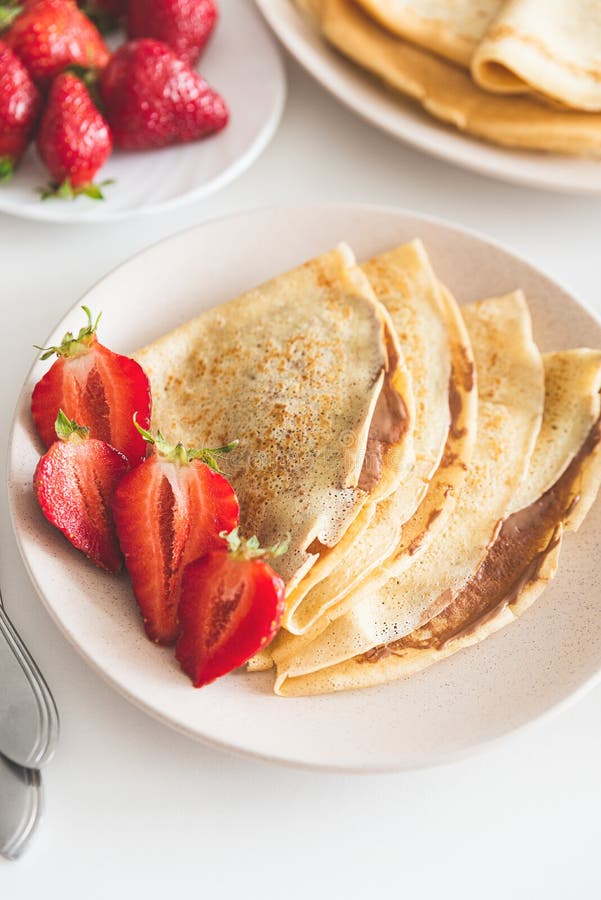 French Crepes with Chocolate Spread and Strawberries on White Table