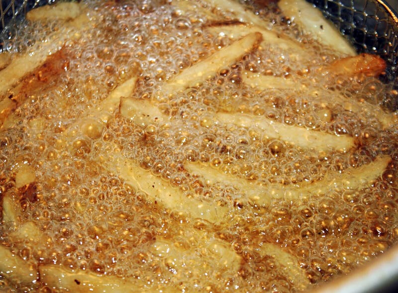 French Fries Cooking and Bubbling in a Deep Fryer Filled with Oil Stock ...