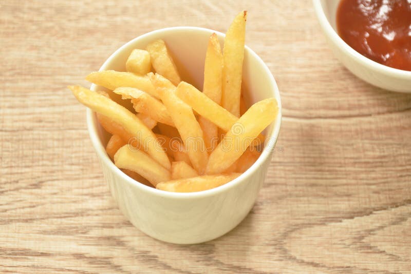 French Fries Mixed with Salt in Cup Dipping Ketchup on Table Stock