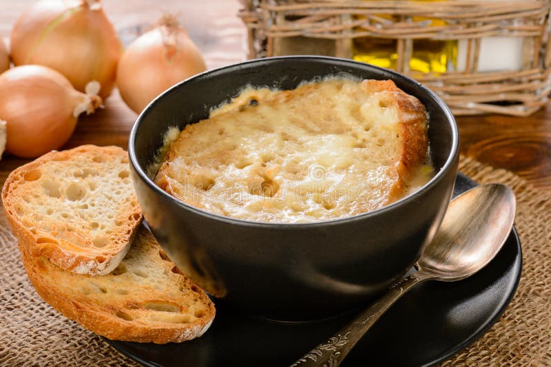 French onion soup with toasts on wooden table.