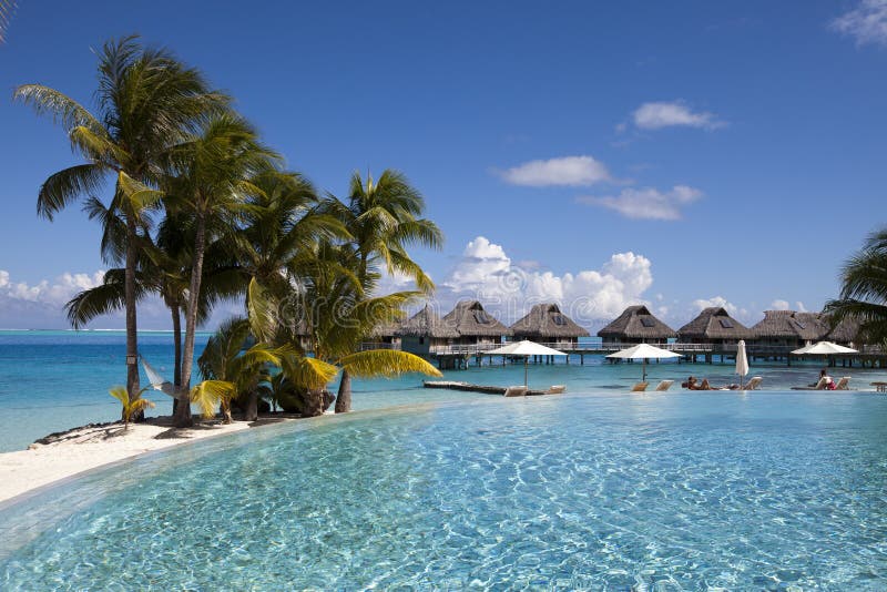 French Polynesia. Over water bungalows, sandy beach with palm trees and pool, Bora Bora