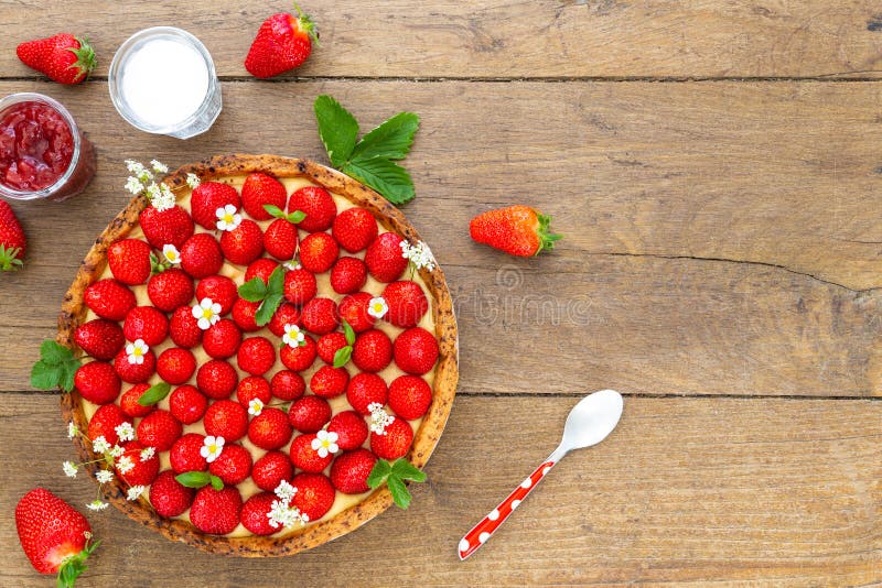 French strawberry tart on oak wood background with teaspoon, jam and sugar jars. Flat Lay, top view with copy space royalty free stock photography French strawberry tart on oak wood background with teaspoon, jam and sugar jars. Flat Lay, top view with copy space royalty free stock photography