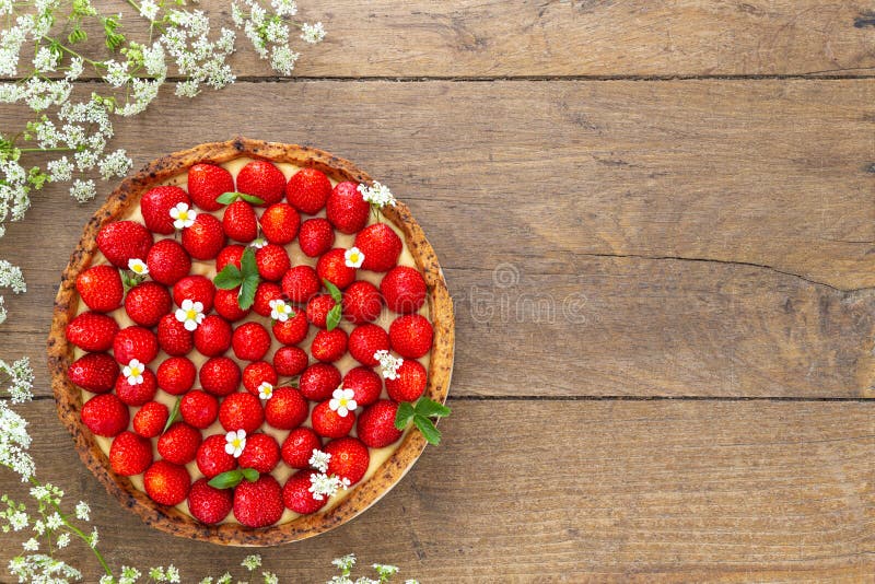 French strawberry tart surrounded by white flower on oak wood background. Flat Lay, top view with copy space royalty free stock photo French strawberry tart surrounded by white flower on oak wood background. Flat Lay, top view with copy space royalty free stock photo