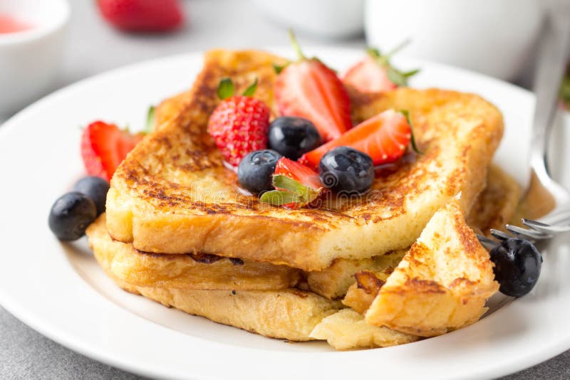 French toast with berries (blueberries, strawberries) and sauce, traditional sweet dessert of bread with egg and milk. Morning baking food