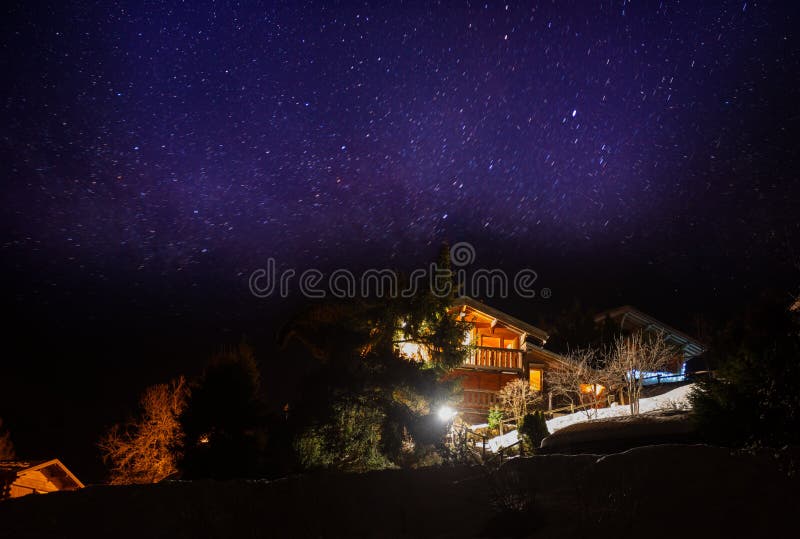 French village with wooden houses chalets over stars in the sky