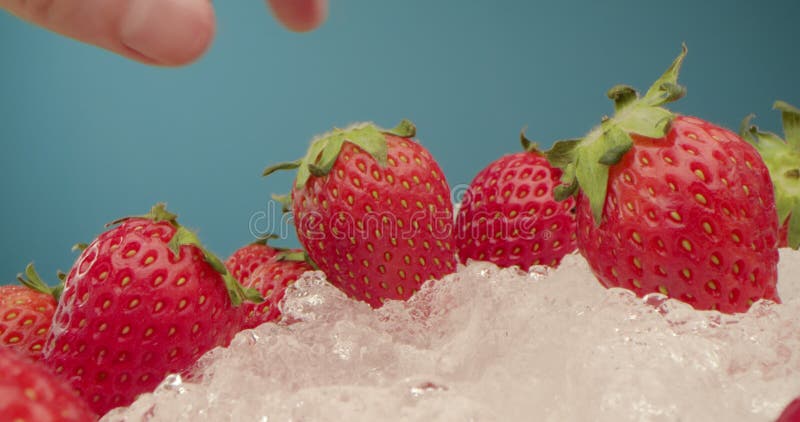 Fresa roja dulce yace en un líquido helado blanco sobre un fondo oscuro. macro detallada a mans