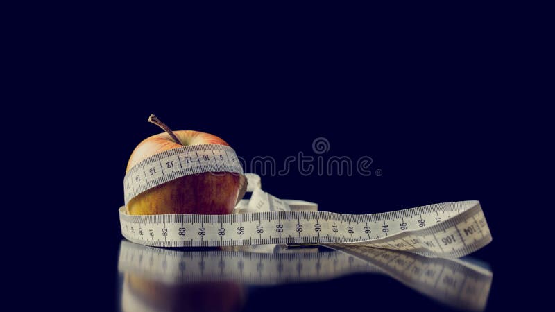 Fresh apple wrapped with a white measuring tape