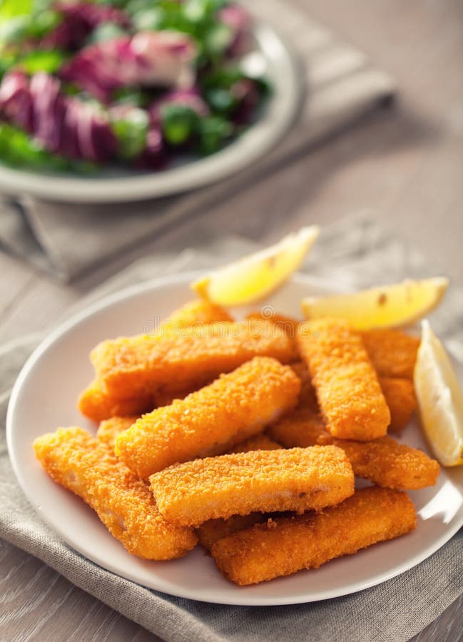 Fresh breaded fish fingers served with mixed salad. royalty free stock photos